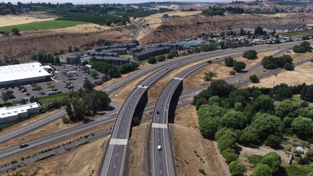 Aerial of multilane highway 12 through suburban valley in Yakima Washington with adjacent commercial buildings and residential housing complexes
