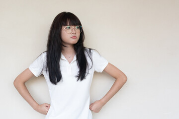 Obraz premium Serious young Asian Thai teenage girl in glasses and white polo shirt looking sideways.