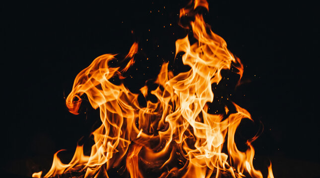 Bright orange fire flames on black background. Intense burning blaze with glowing sparks.