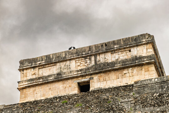 Two black vultures perched on top of the Kukulkan pyramid at Chichen Itza, Mexico