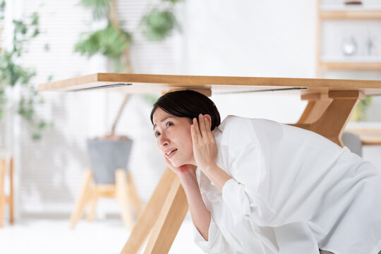 地震が起きてテーブルの下に隠れる女性