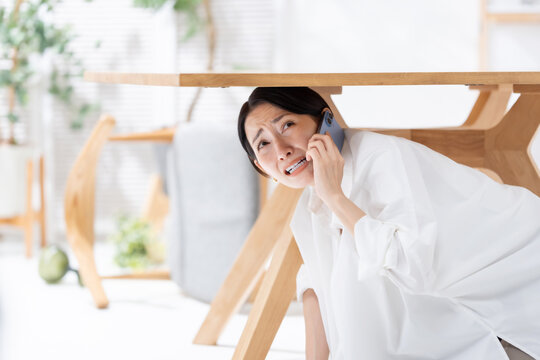 地震が起きてテーブルの下に隠れる女性