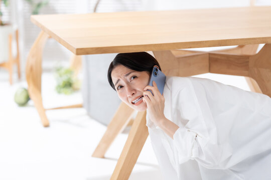 地震が起きてテーブルの下に隠れる女性