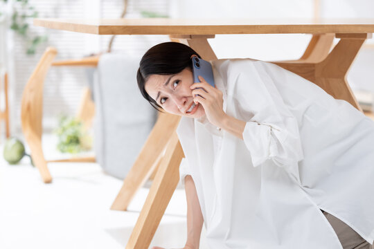 地震が起きてテーブルの下に隠れる女性