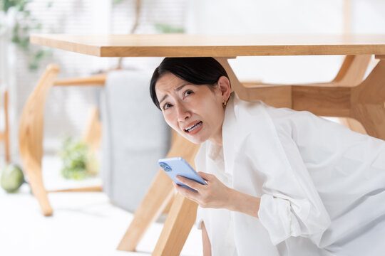 地震が起きてテーブルの下に隠れる女性