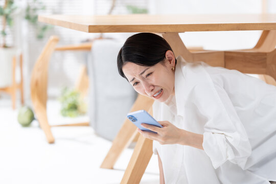 地震が起きてテーブルの下に隠れる女性
