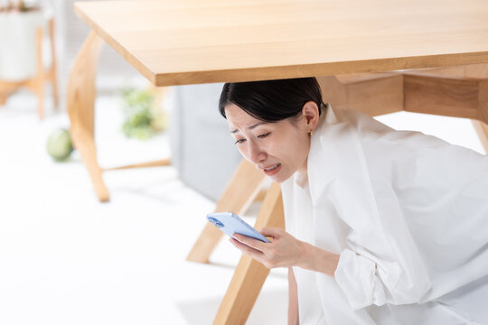 地震が起きてテーブルの下に隠れる女性