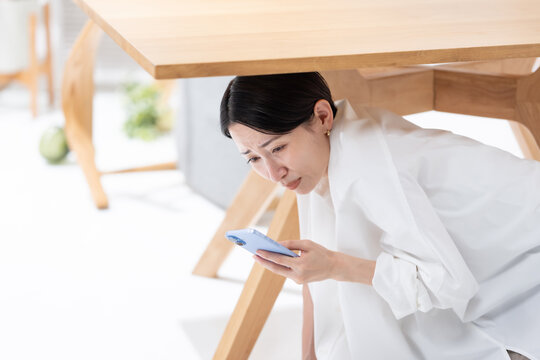 地震が起きてテーブルの下に隠れる女性