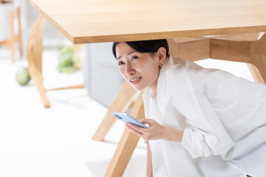 地震が起きてテーブルの下に隠れる女性