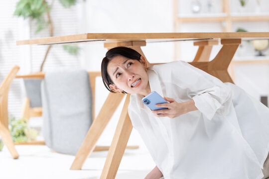 地震が起きてテーブルの下に隠れる女性