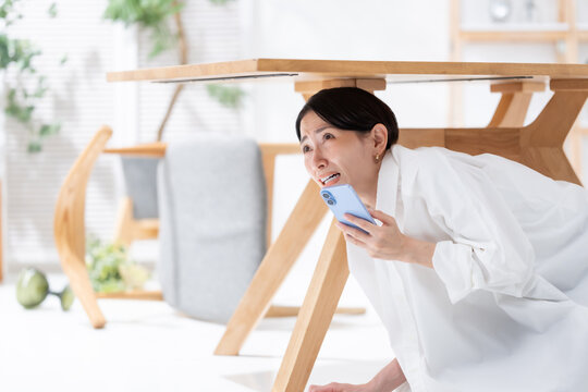 地震が起きてテーブルの下に隠れる女性