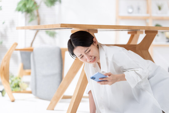 地震が起きてテーブルの下に隠れる女性