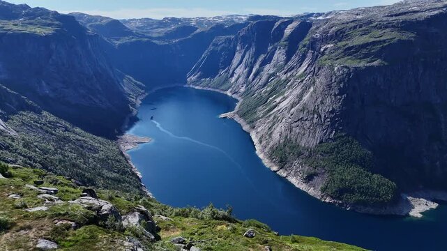 Drone panorama of deep fjord lake Ringedalsvatnet framed by steep cliffs and green highlands in Hardanger, Norway on a clear summer day.