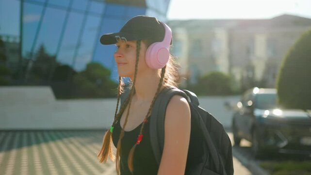 Gen Z, Smiling teenage girl walking outdoors in bright sunlight wearing headphones. preteen