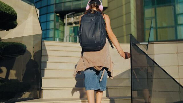 Gen Z, Teenager with backpack walking up stairs towards a modern glass building. preteen