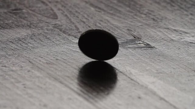 A single two euro coin spinning on a wooden surface in slow motion
