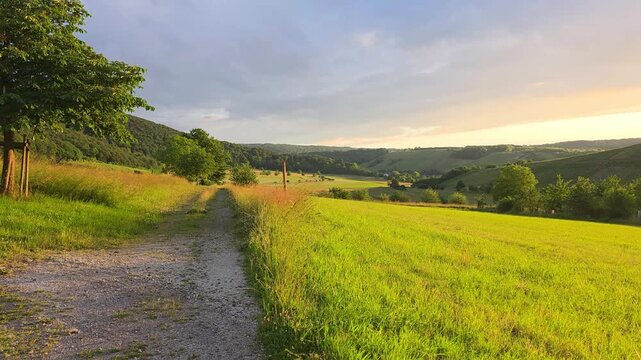 Summer sunset view over beautiful rolling fields and hills of the Mosel region of Germany, slow panning motion