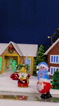 A yellow car drives past a large Christmas village