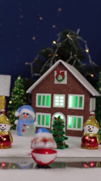 Against the backdrop of a Christmas village, a yellow car drives by and an unusual Santa Claus jumps out