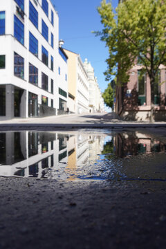 Low angle view of city street reflected in a puddle