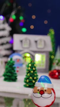 A yellow car drives up to a large Christmas village with Christmas trees and snowmen near colorful houses