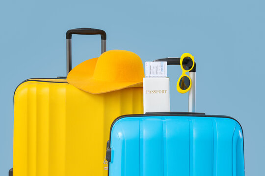 Yellow and blue travel suitcases with passport, boarding pass, hat, and sunglasses, vacation and tourism