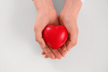 Obraz premium Human hands holding a red heart, health care and medical support, love and compassion, isolated on a white background