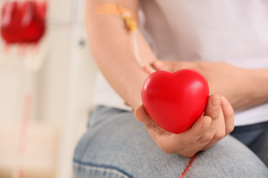 Person donating blood holding a red heart, medical procedure and healthcare concept, blood donation campaign