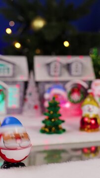 Ahead of a large Christmas town with Christmas trees and snowmen, near colorful houses, an unusual Santa Claus pops out