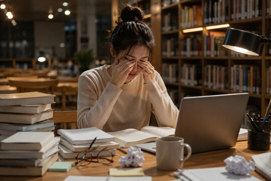 Exhausted female student feeling tired and frustrated at a desk with a computer.