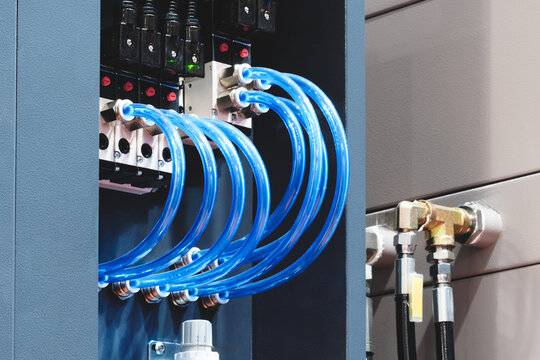 Transparent plastic tubes of pneumatic conveyor drive and rubber tubes of hydraulic drive are connected to industrial machin, tech industrial technology background