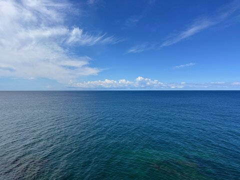Open ocean blue waters and blue sky with clouds horizon