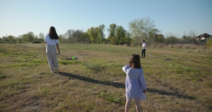 Mother with Children Throw Flying Disk Playing Outside. Family spend time together on nature. 4K 10-bit