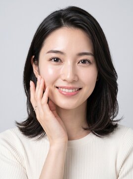 Young Japanese woman touching her cheek with a clean minimalist backdrop, everyday skincare and beauty concept, well suited for lifestyle and beauty blogs