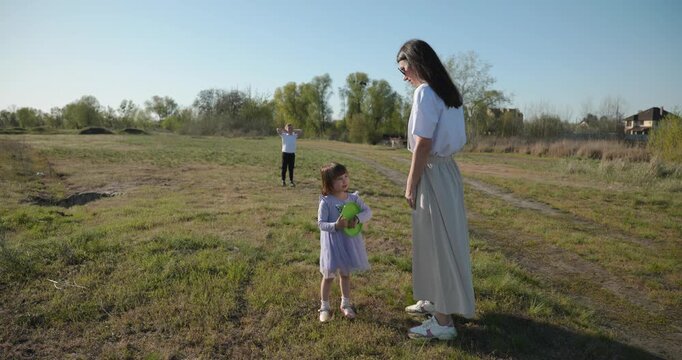 Mother with Children Throw Flying Disk Playing Outside. Family spend time together on nature. 4K 10-bit