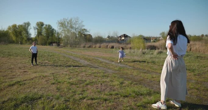 Mother with Children Throw Flying Disk Playing Outside. Family spend time together on nature. 4K 10-bit