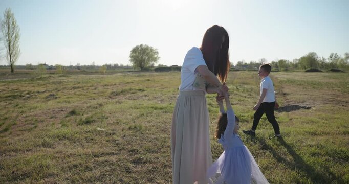 Mother with Children Throw Flying Disk Playing Outside. Family spend time together on nature. 4K 10-bit