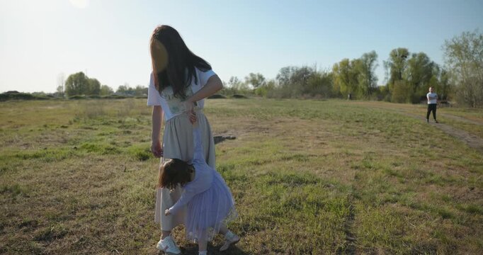 Mother with Children Throw Flying Disk Playing Outside. Family spend time together on nature. 4K 10-bit