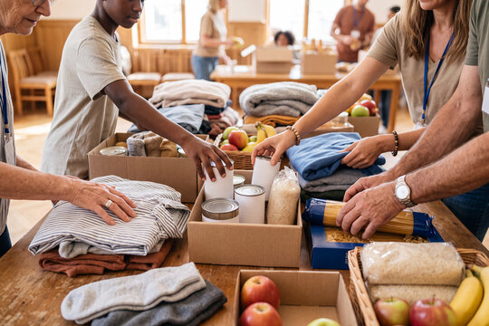 Diverse Hands Sorting Donated Food and Clothing Items on a Community Center Table
