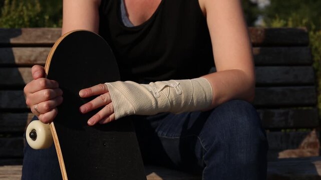 Unsuccessful fall from skateboard and hand injury. Injured hand in medical bandage next to skateboard close-up. Shot highlights risks of street sports, training failures and rehabilitation process