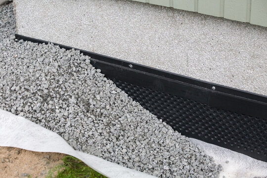 Foundation waterproofing membrane and drainage gravel around house. House foundation drainage system with dimple membrane installation.