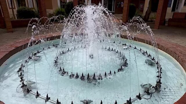 Close up slow motion video of crystal clear water fountain jet creating a dome shape splash with shiny flying droplets. Macro liquid physics and refreshing nature jet background. High quality 4K video