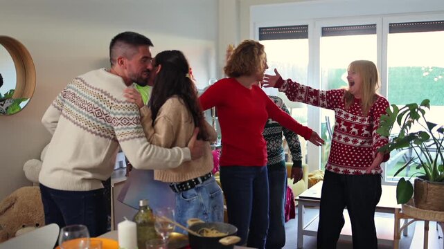 Joyful family members wearing festive christmas sweaters are greeting guests with warm hugs and kisses, arriving with gifts for a holiday dinner party in a cozy, decorated home