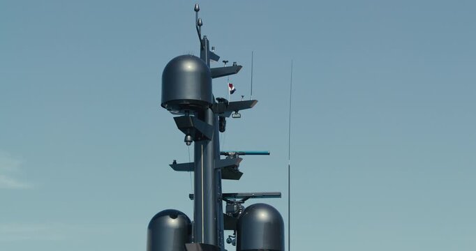 Close view of a cruise ship radar mast with navigation antennas and the Croatian flag against a clear blue sky.