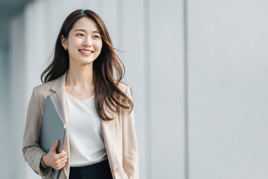 ノートPCを持ち歩く笑顔の日本人女性 Generative AI