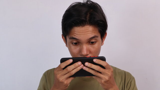 Asian young man playing game on smartphone seriously