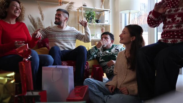 Happy multi generational family and friends celebrating together on christmas day, laughing and clapping with joy and excitement in a cozy living room decorated for the festive winter holiday