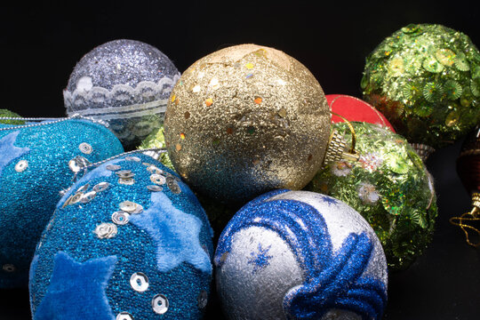 Gold glitter Christmas bauble surrounded by silver blue-patterned ball, egg-shaped sequin ornaments, and green baubles