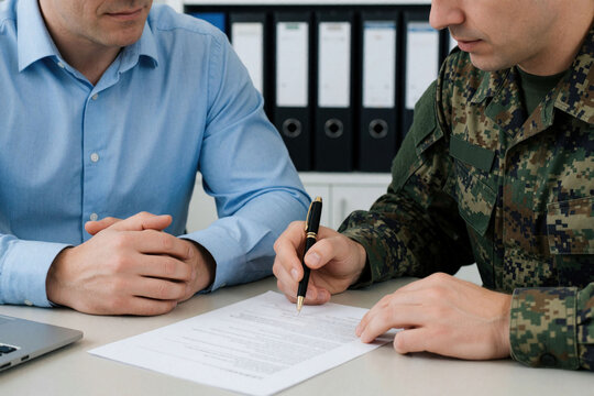 Man in blue shirt and soldier in uniform sign contract document at desk. They complete paperwork together in office. Collaboration between civilian and army.