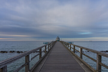Fototapeta premium Straight wooden pier extending towards tauchgondel diving capsule over calm Baltic ocean